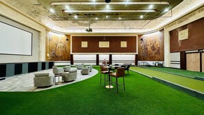 Une salle de conférence dotée d’un tapis vert, d’un écran de projection et d’un aménagement pour accueillir les participants.
