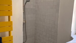 Ett badrum med dusch, ett gult handduksställ och ett handfat.