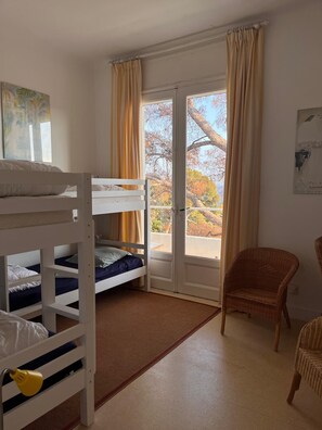 A room with bunk beds, a wicker chair, and a view through a glass door. - Rayol, 5-bedroom villa with pool, 100 m from the beach (Rayol-Canadel-sur-Mer)