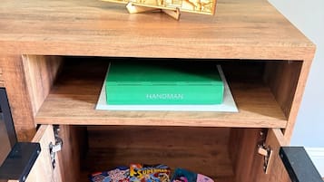 A wooden cabinet with a map on top, a green box labeled 'HANGMAN' in the middle, and a collection of colorful books at the bottom.