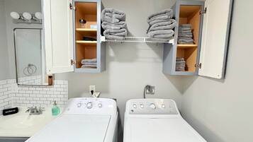 A laundry room with two washing machines, a mirror, and towel storage.