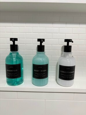 Three bottles of Lusspa personal care products on a white tiled shelf.