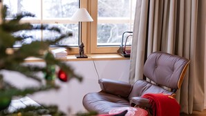 A cozy room with a leather sofa, a small table, a Christmas tree, and a window with curtains. - La Tzoumaz Lodge, 4 Vallées luxury chalet, daily housekeeping, sleeps 10 to 12 (Riddes)