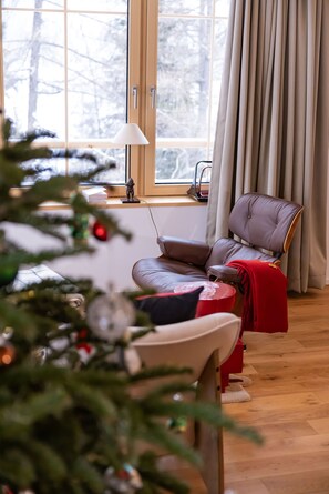 A cozy room with a leather sofa, a small table, a Christmas tree, and a window with curtains. - La Tzoumaz Lodge, 4 Vallées luxury chalet, daily housekeeping, sleeps 10 to 12 (Riddes)