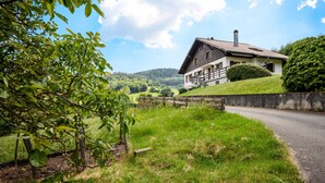 A house with a sloped roof, a chimney, and a stone wall.