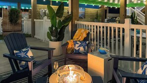 Un patio con mobiliario exterior, una chimenea y vista al océano.