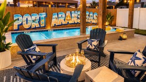 Un área junto a la piscina con sillas tipo Adirondack, una fogata y un letrero que dice 'PORT FRANZAS'.