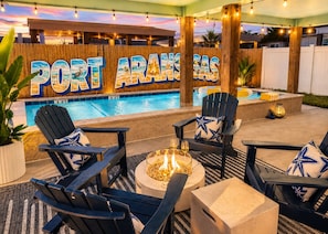 Ein Poolbereich mit Adirondack-Stühlen, einer Feuerstelle und einem Schild mit der Aufschrift 'PORT FRANZAS'.