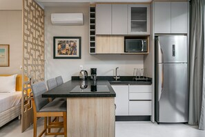 Una cocina compacta con refrigerador, microondas y cafetera sobre la encimera.