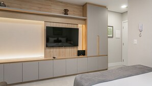 Ein modernes Schlafzimmer mit Bett, Wand-Fernseher, Nachttisch und Kleiderschrank.