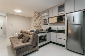 Cozinha moderna com forno embutido, micro-ondas e frigorífico de aço inoxidável.