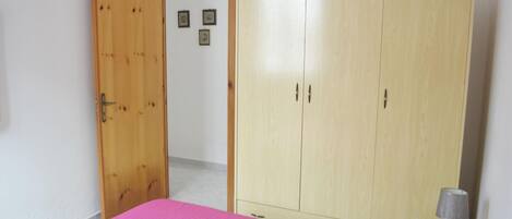 Un dormitorio con una cama, un armario y una puerta que da a otra habitación.
