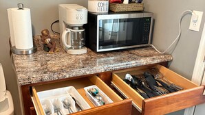 Et køkken med kaffemaskine, mikroovn og en skuffeorganisator.