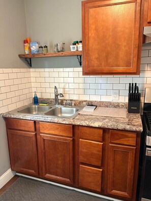 A kitchen with granite countertops, wooden cabinets, a double sink, and a stove.