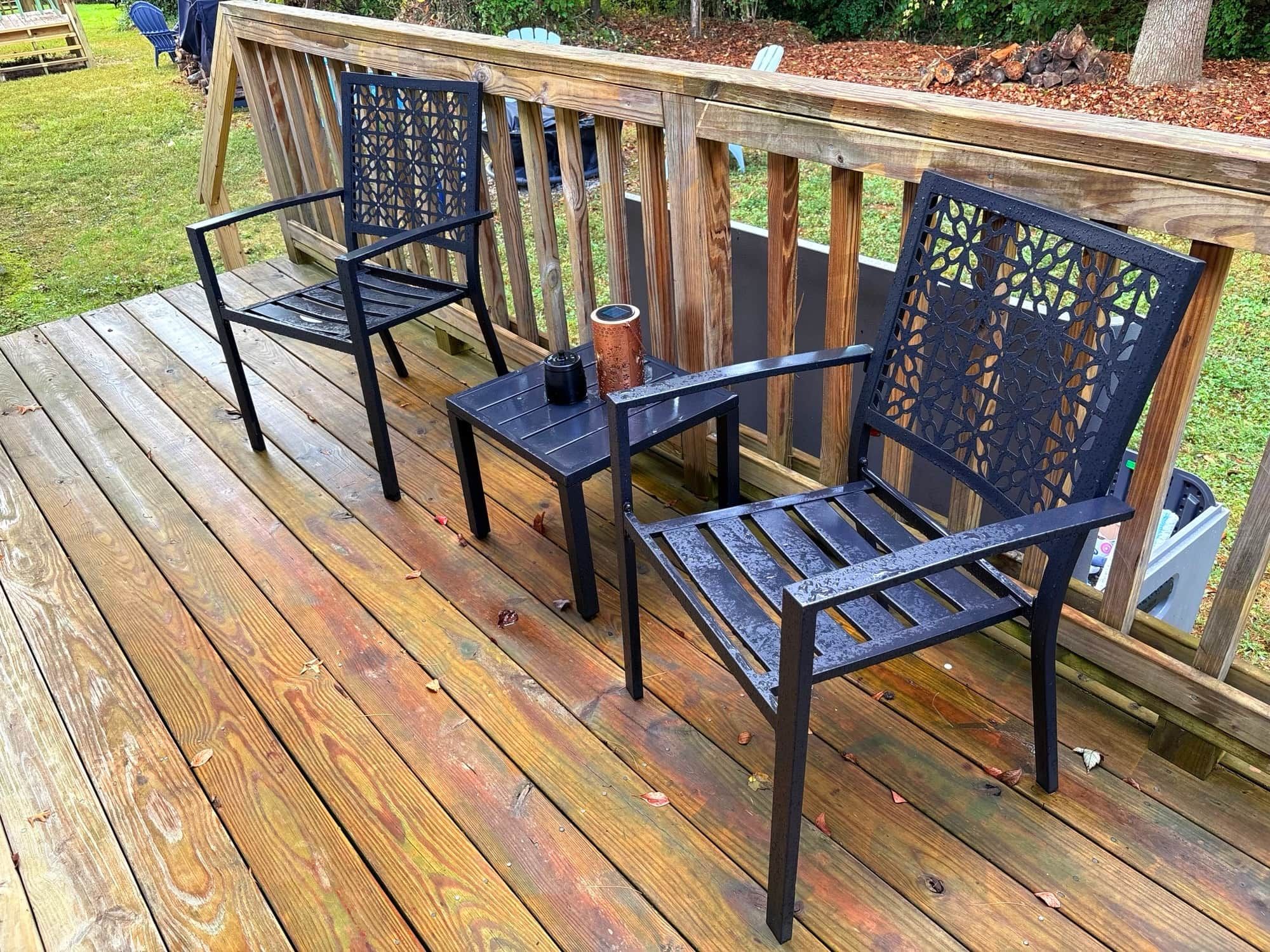 Eine Holzterrasse mit zwei Metallstühlen und einem kleinen Tisch.