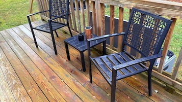 Eine Holzterrasse mit zwei Metallstühlen und einem kleinen Tisch.
