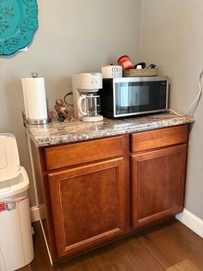 A kitchen with a coffee maker, microwave, and a coffee filter basket on the counter.