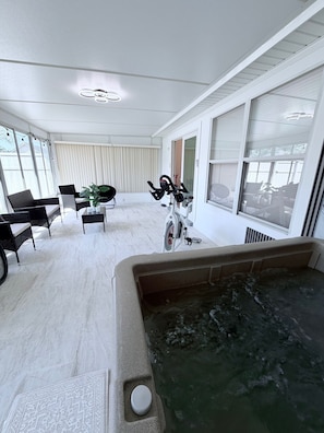 Ein Zimmer mit Whirlpool, einem Fahrrad und einer Sitzecke mit Stühlen und einem Tisch.