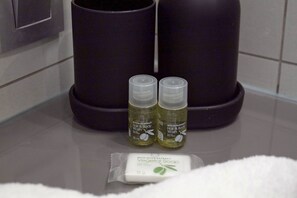 Two bottles of hair and body wash, a bar of soap, and a trash can in a bathroom. - Appartement 6B - MyResidenced'Azur (Beausoleil)