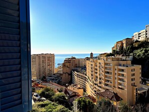 A coastal cityscape with high-rise buildings, a clear sky, and a view of the sea. - Appartement 6B - MyResidenced'Azur (Beausoleil)