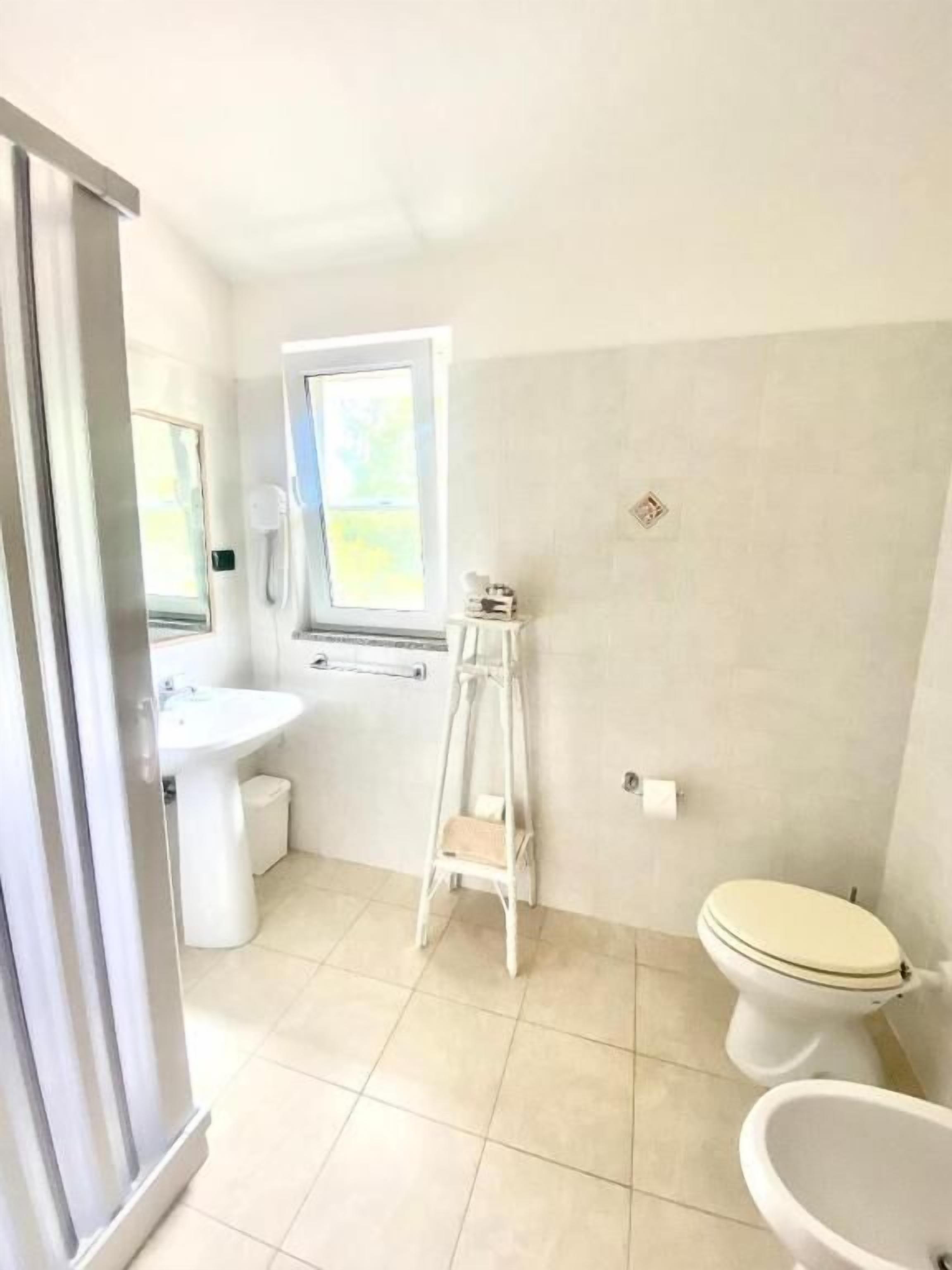 A bathroom with a toilet, sink, and window.