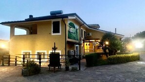 Un edificio con fachada amarilla, un balcón y un área de acceso empedrada.