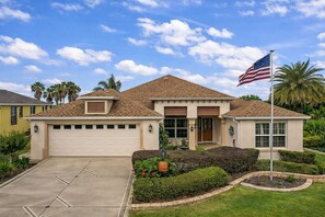 Een gelijkvloers huis met garage, voortuin en een vlaggenmast met de Amerikaanse vlag.