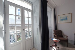 Une pièce avec une porte blanche, une chaise, une table avec un livre et un tableau encadré au mur.