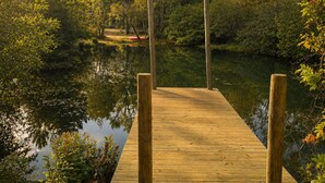 Un moll de fusta s'endinsa en un cos d'aigua tranquil·la, envoltat de vegetació i arbres densos.