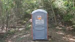 Un lavabo portàtil amb la inscripció 'Rocky Top Restrooms' i un número de contacte.