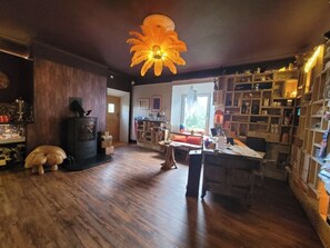 Uma sala de estar acolhedora com piso de madeira, lareira, sofá, mesa de jantar e estante de livros.