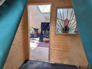 Interior de madeira com claraboia, uma cama e janela com padrão geométrico.