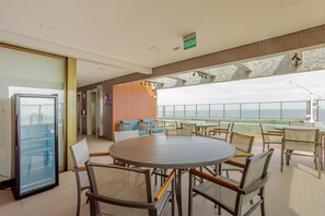 Een moderne zithoek met een ronde tafel, stoelen, een koelkast en uitzicht op de oceaan.