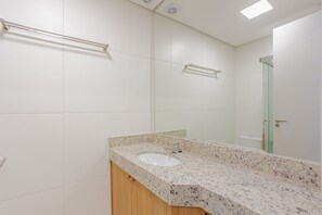 Een badkamer met een witte wastafel, een spiegel en een handdoekhouder.
