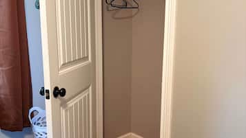 A room with a door, a coat rack, a blue and yellow blanket, and a white basket.