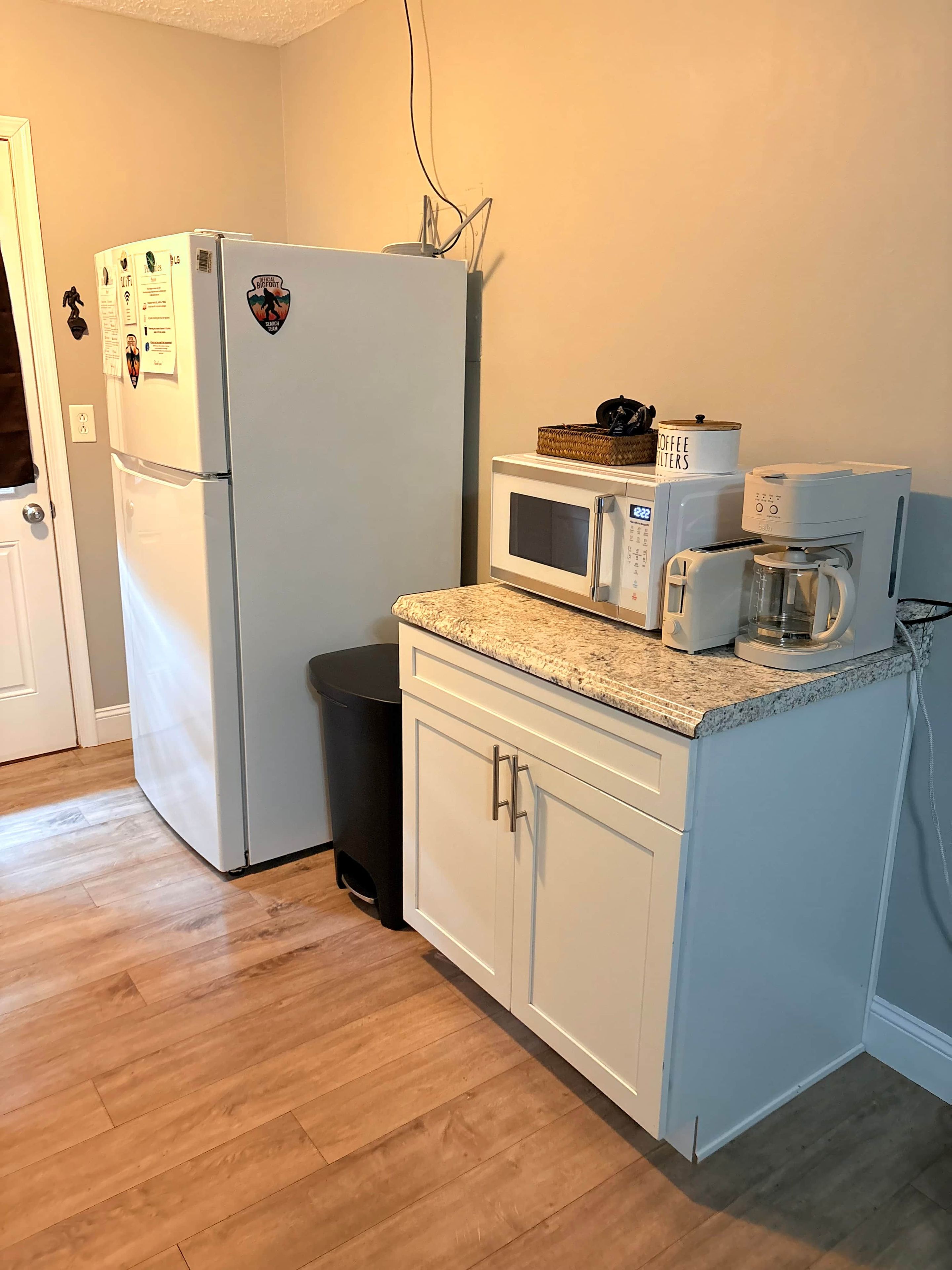 Cozinha compacta equipada com geladeira, micro-ondas, torradeira e cafeteira.