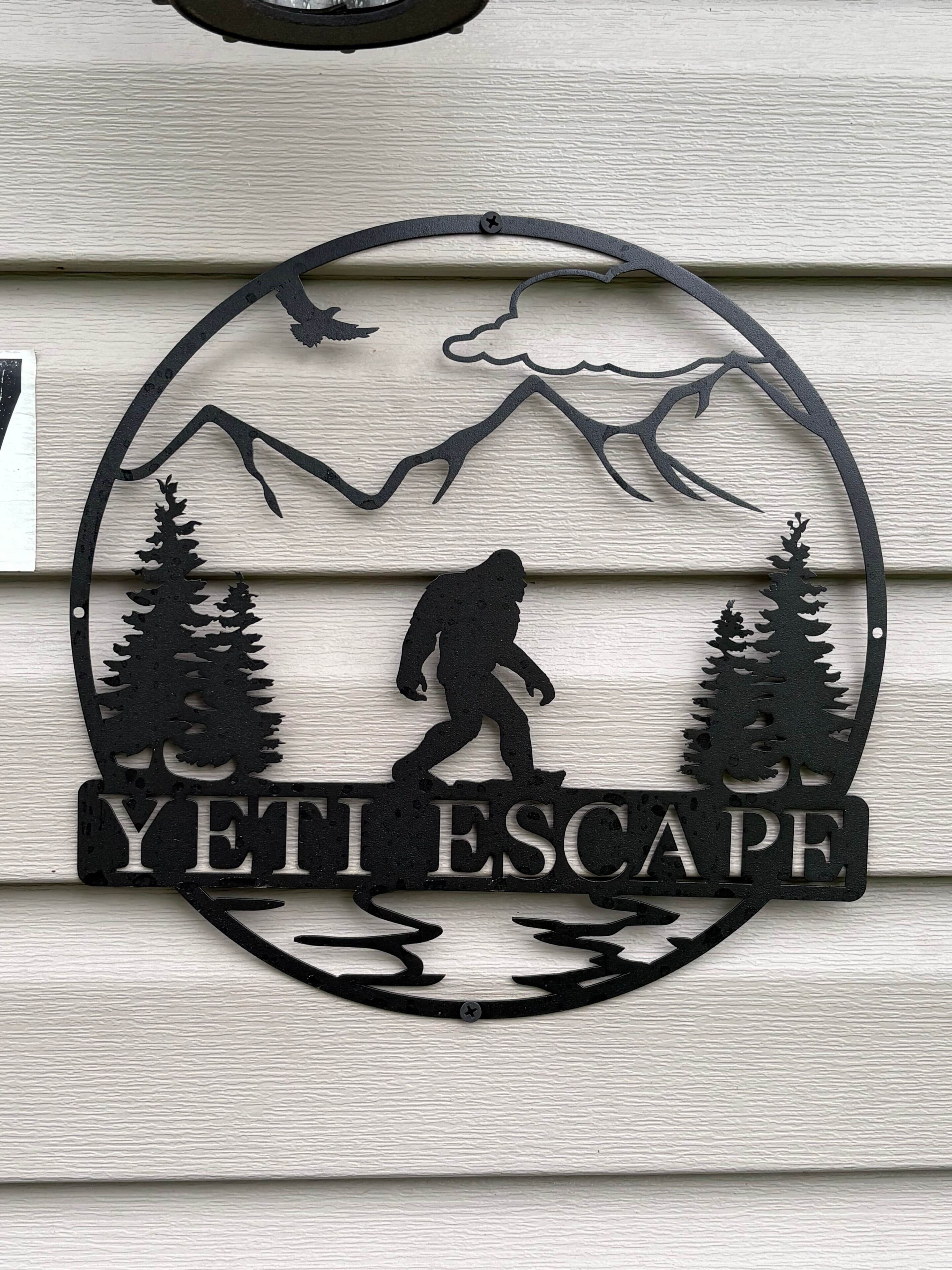 Une plaque métallique représentant la silhouette d’un randonneur et de montagnes, avec l’inscription « YETI ESCAPE ».