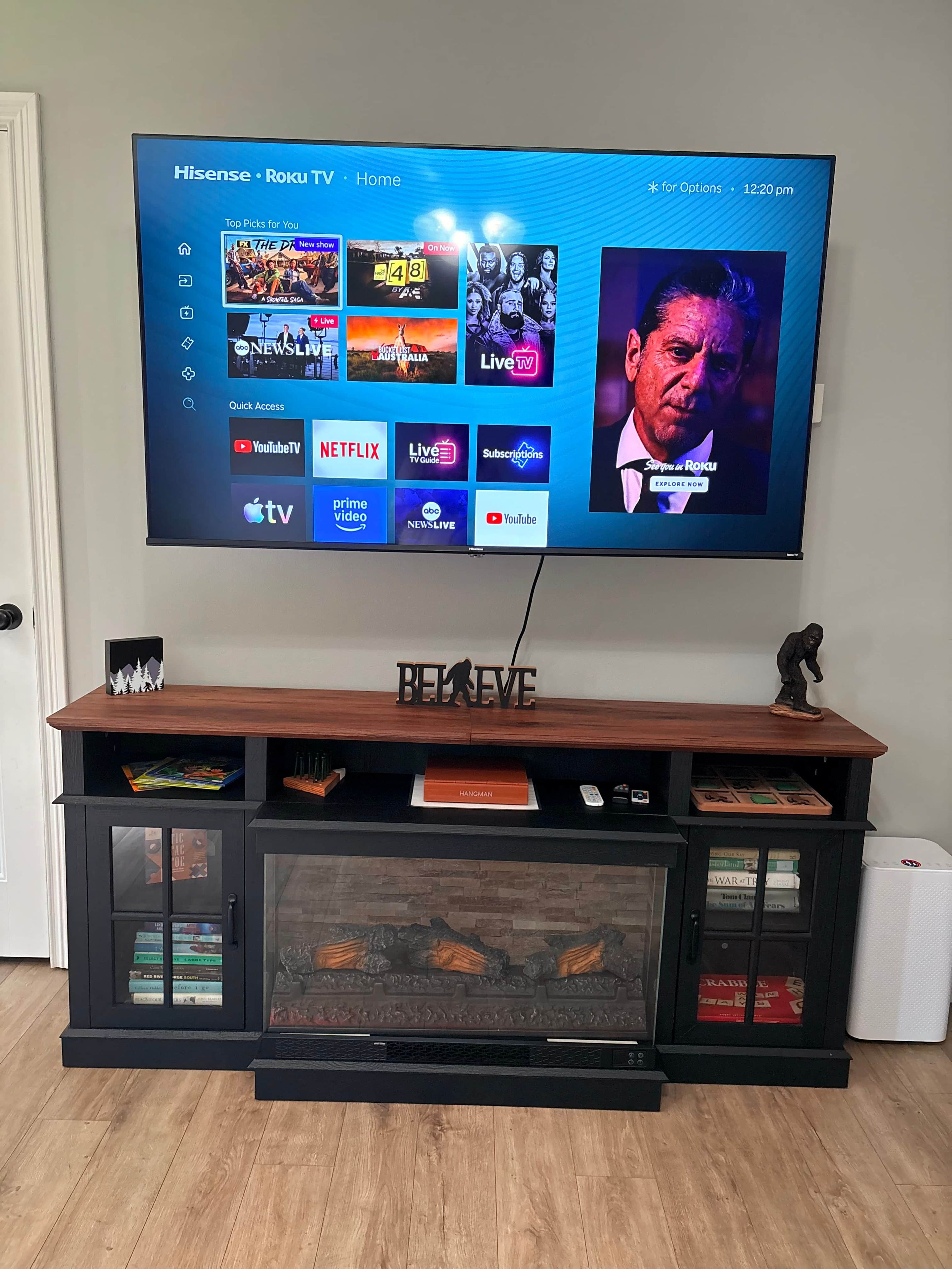 A television mounted on a wooden entertainment center with a digital display showing various streaming services.