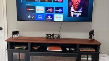 A television mounted on a wooden entertainment center with a digital display showing various streaming services.