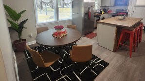 Una cocina moderna con una isla central, comedor con sillas y una planta en maceta.