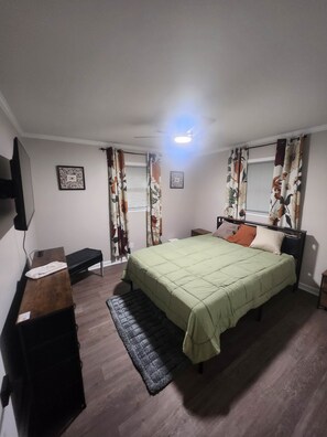 A bedroom with a bed, bedside tables, a bench, a rug, and curtains.