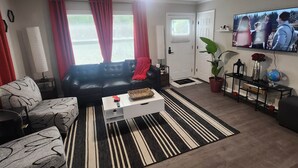 Una sala de estar con un sofá, una mesa de centro, un televisor y una planta en maceta.