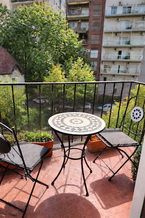 A balcony with a round table and two chairs, surrounded by a metal fence. - Studio apartment in Palermo (Buenos Aires)