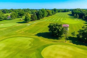 A golf course with a clubhouse, trees, and a clear sky. - Serene 3BR Retreat, walk to URMC, RIT & Golisano (Rochester)