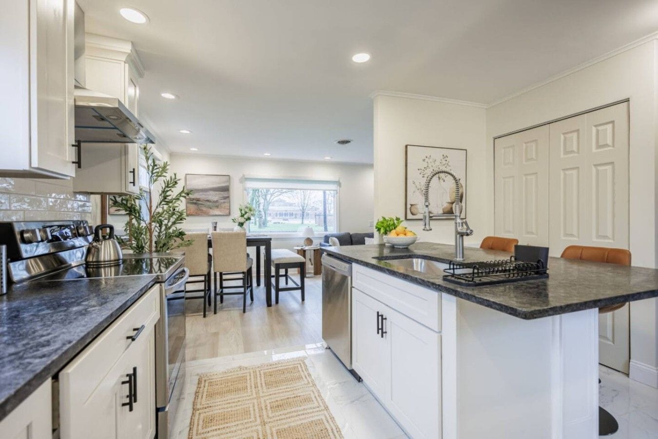A modern kitchen with a central island, white cabinetry, and a view to the dining area.
