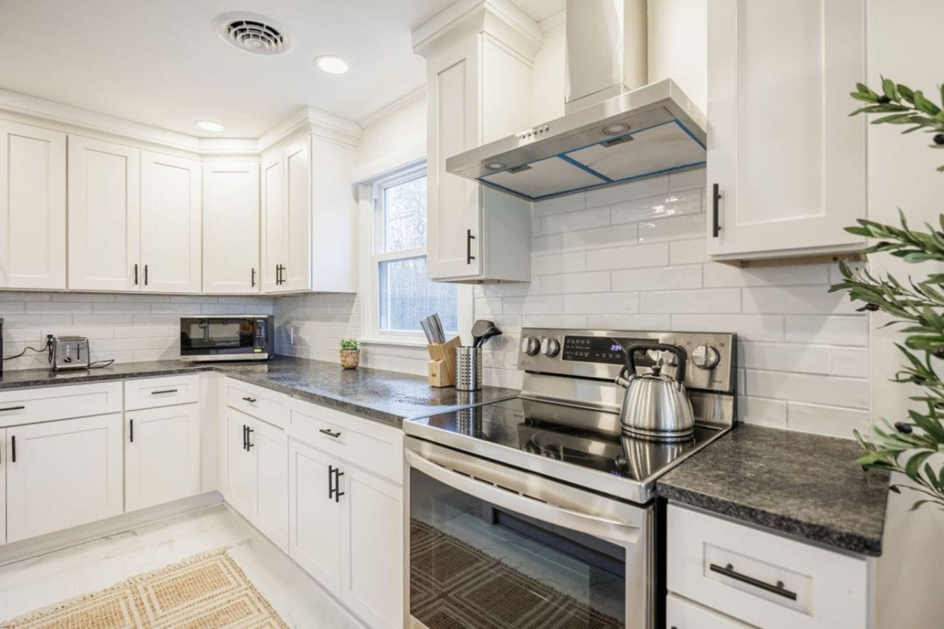 A modern kitchen with white cabinetry, a stainless steel range, and a built-in oven.