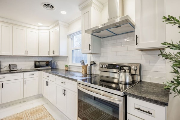 A modern kitchen with white cabinetry, a stainless steel range, and a built-in oven.