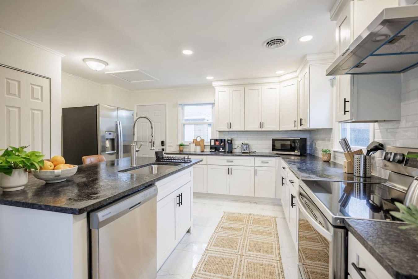 A modern kitchen with white cabinetry, granite countertops, and stainless steel appliances.