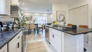Une cuisine moderne avec des meubles blancs, un îlot central et un coin repas avec des chaises.