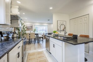 Une cuisine moderne avec des meubles blancs, un îlot central et un coin repas avec des chaises.
